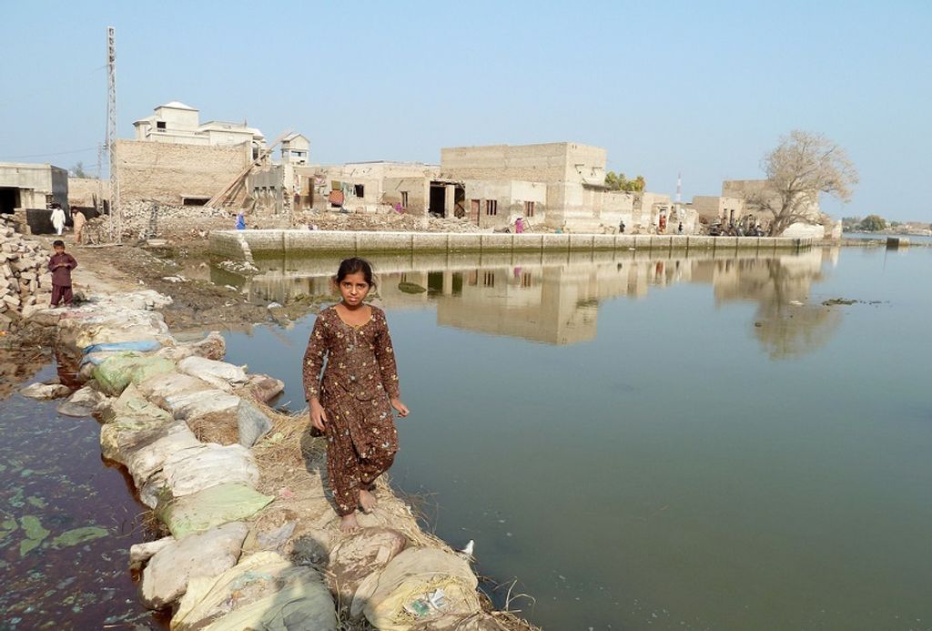 A young girl walks across a makeshift path through stagnant floo
